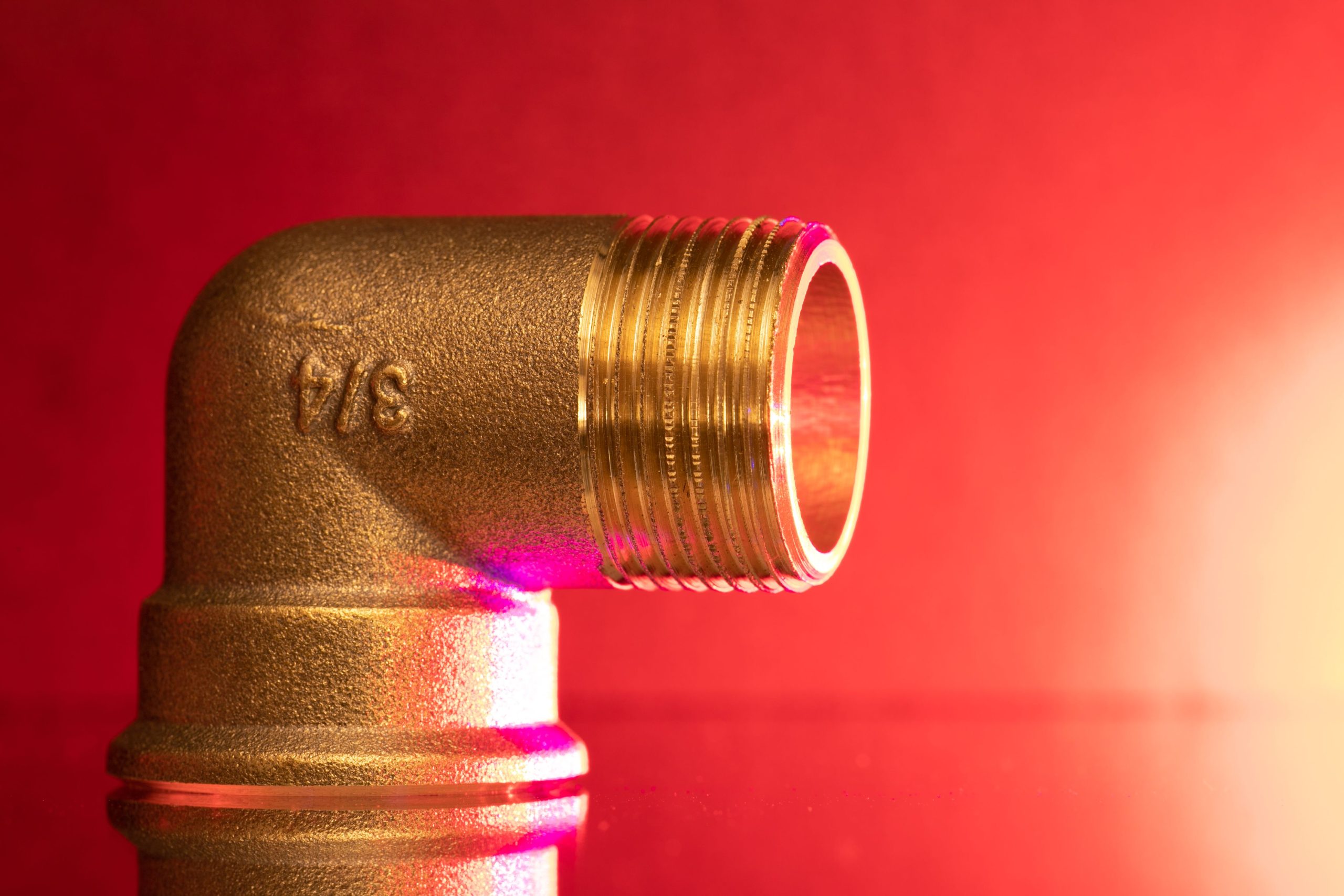 Raccord coude laiton brillant fond rouge