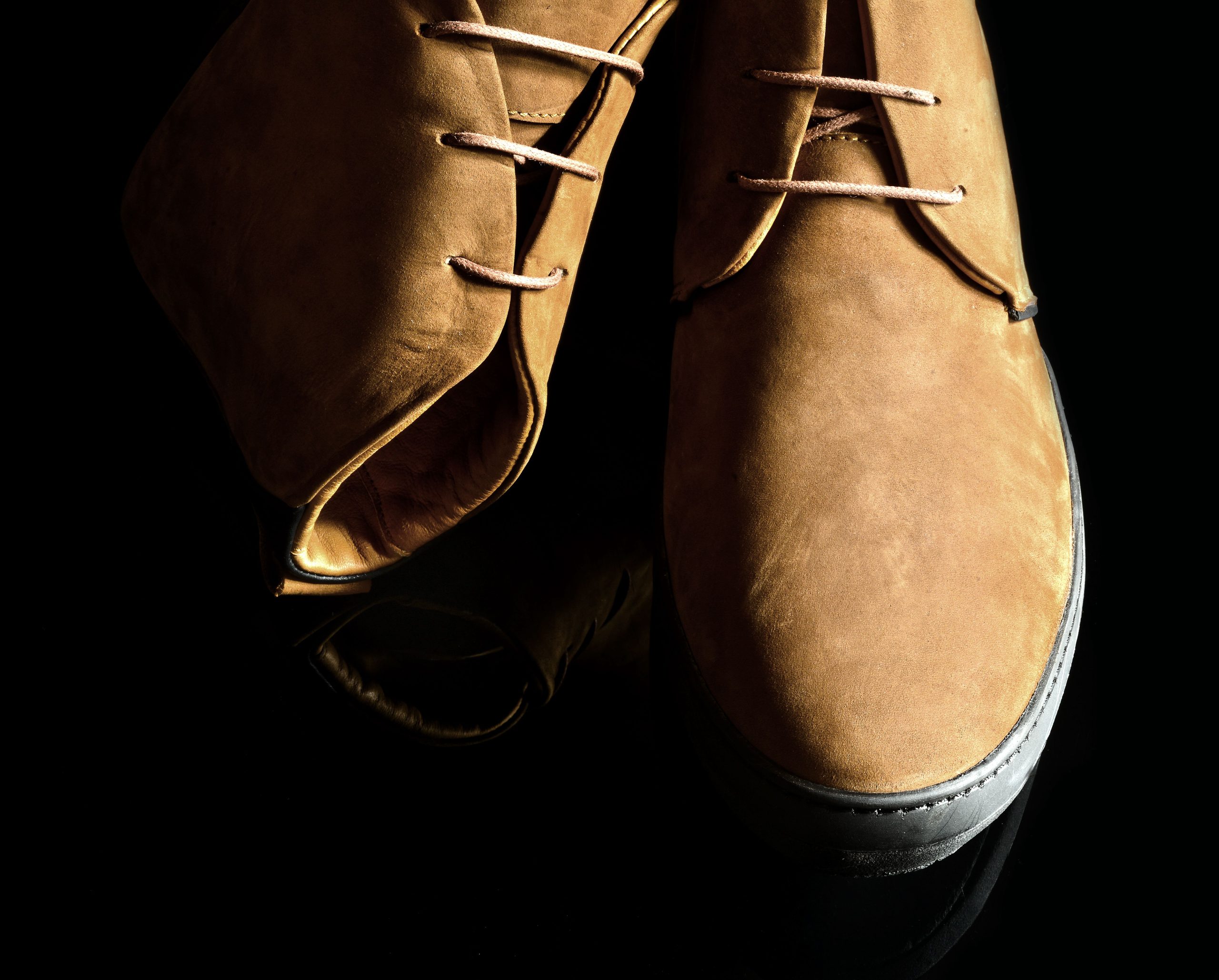 Chaussures daim lacées sur surface noire brillante