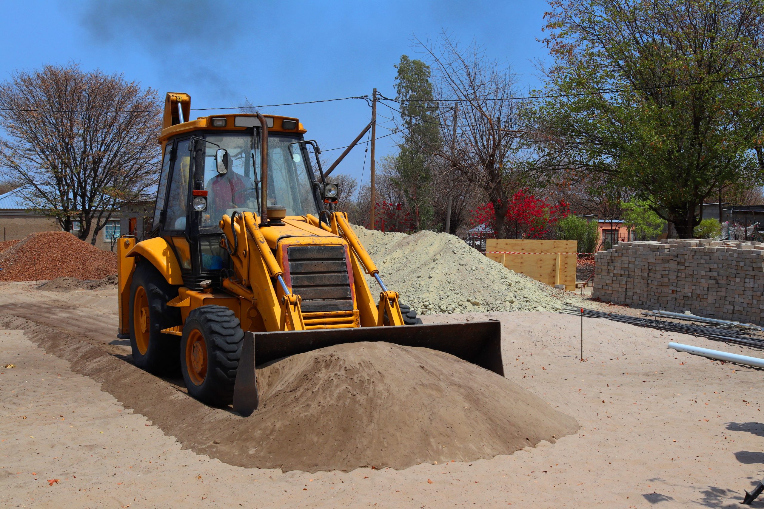 Tractopelle jaune deplacant du sable